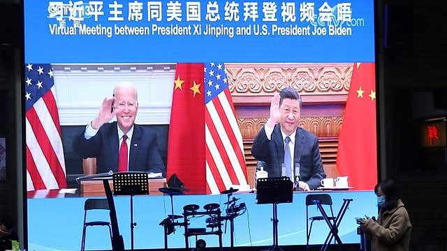 两人一见面就隔着屏幕向对方挥手致意（图为北京一家餐馆在大屏幕播出拜登和习近平举行视像会晤的新闻）。