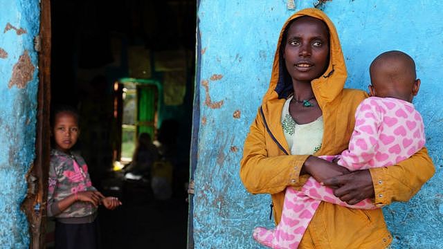 A woman and her children look on as food aid and mattresses are delivered to the Day Care centre turned IDP camp they currently reside in on October 11, 2021