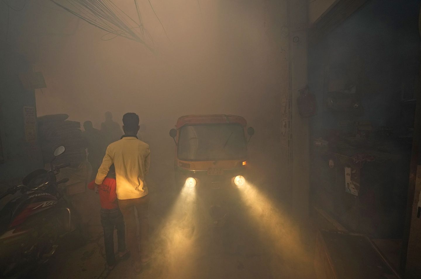 2021年10月27日，通勤者在印度新德里的一个人群密集、烟雾弥漫的街区穿过。（AP)