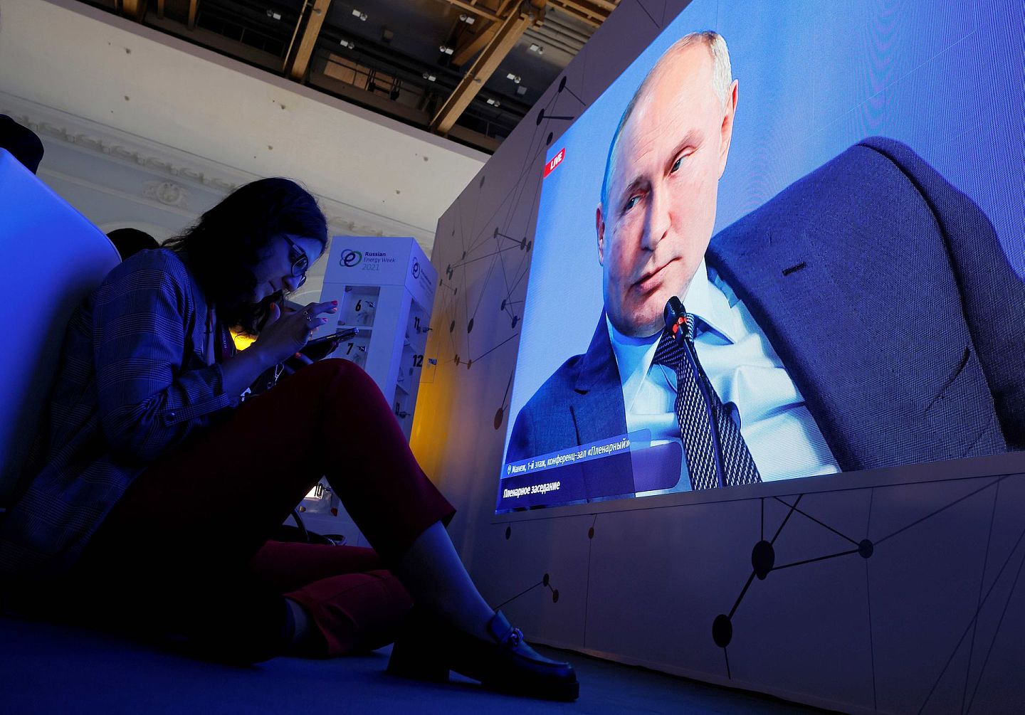 2021年10月13日，一名媒体记者在电视屏幕前观看俄罗斯总统普京讲话。（Reuters）