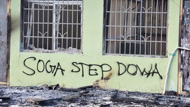 Anti-government messages adorn a burnt-out building in Honiara on November 27, 2021, as a tense calm returned after days of intense rioting that left at least three dead and reduced swathes of the city to smouldering ruins.