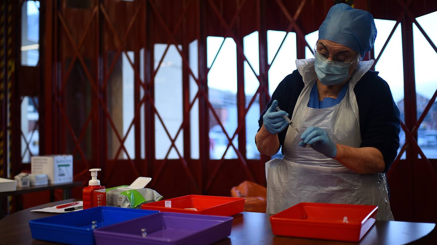 英国新冠肺炎疫情：图为12月4日，英国政府在贝尔法斯特一间消防局内设置临时新冠疫苗接种中心，一名护士正处理辉瑞新冠疫苗，准备为到访中心的民众接种。 （Reuters）