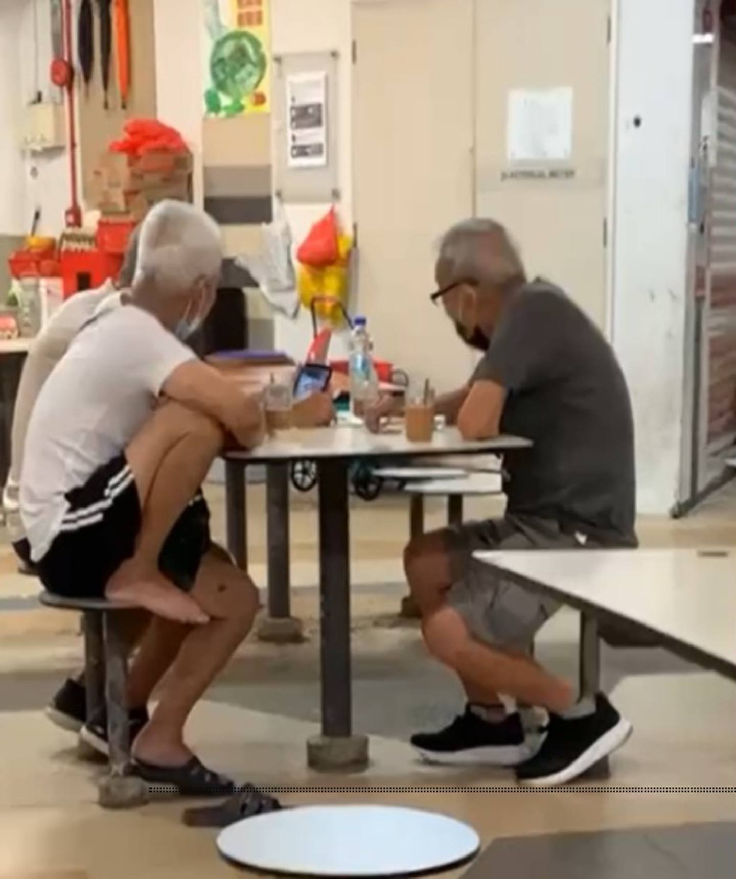 3名老翁在1张长桌上围坐，观赏手机内的影片并看得非常入神，而手机发出的声响却令人异常尴尬，原来他们正公然地播放成人影片。 （影片截图）