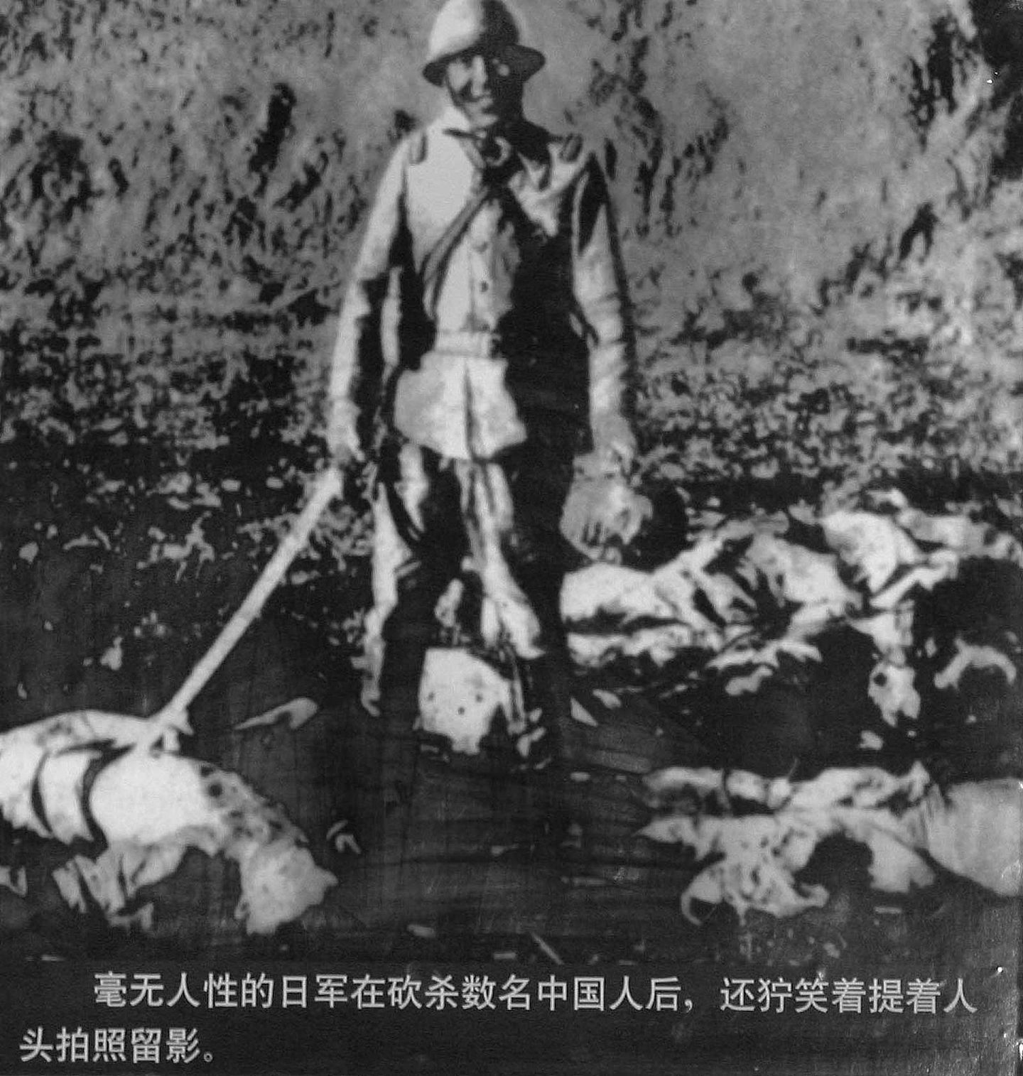 侵华日军在砍杀数名中国人后，提着人头笑着拍照留影。（图源：VCG）