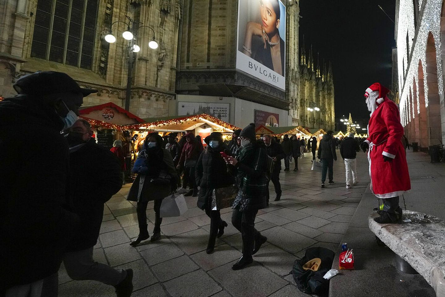 意大利新冠肺炎疫情：图为2021年12月24日，米兰大教堂外一名身穿圣诞老人服装的人在等待途人打赏。（AP）