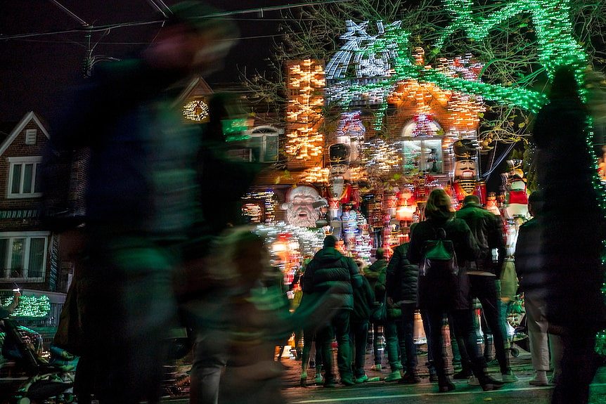 a group of people stand outside a lights and decorations display at a house in Brooklyn, New York