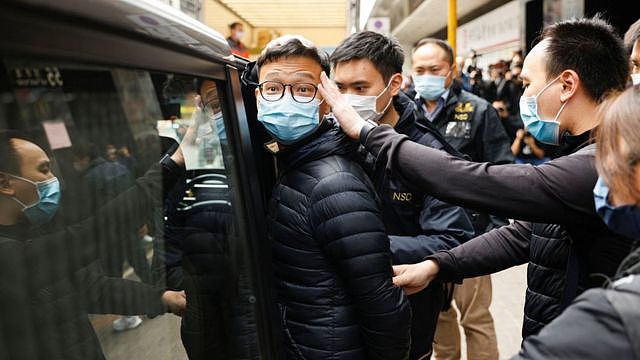 香港观塘《立场新闻》办公室所在大楼外警察国安处探员将《立场新闻》署理总编辑林绍桐押上车（29/12/2021）
