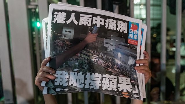 香港将军澳壹传媒总部大楼外一名《苹果日报》雇员举起最后一期报纸（24/6/2021）
