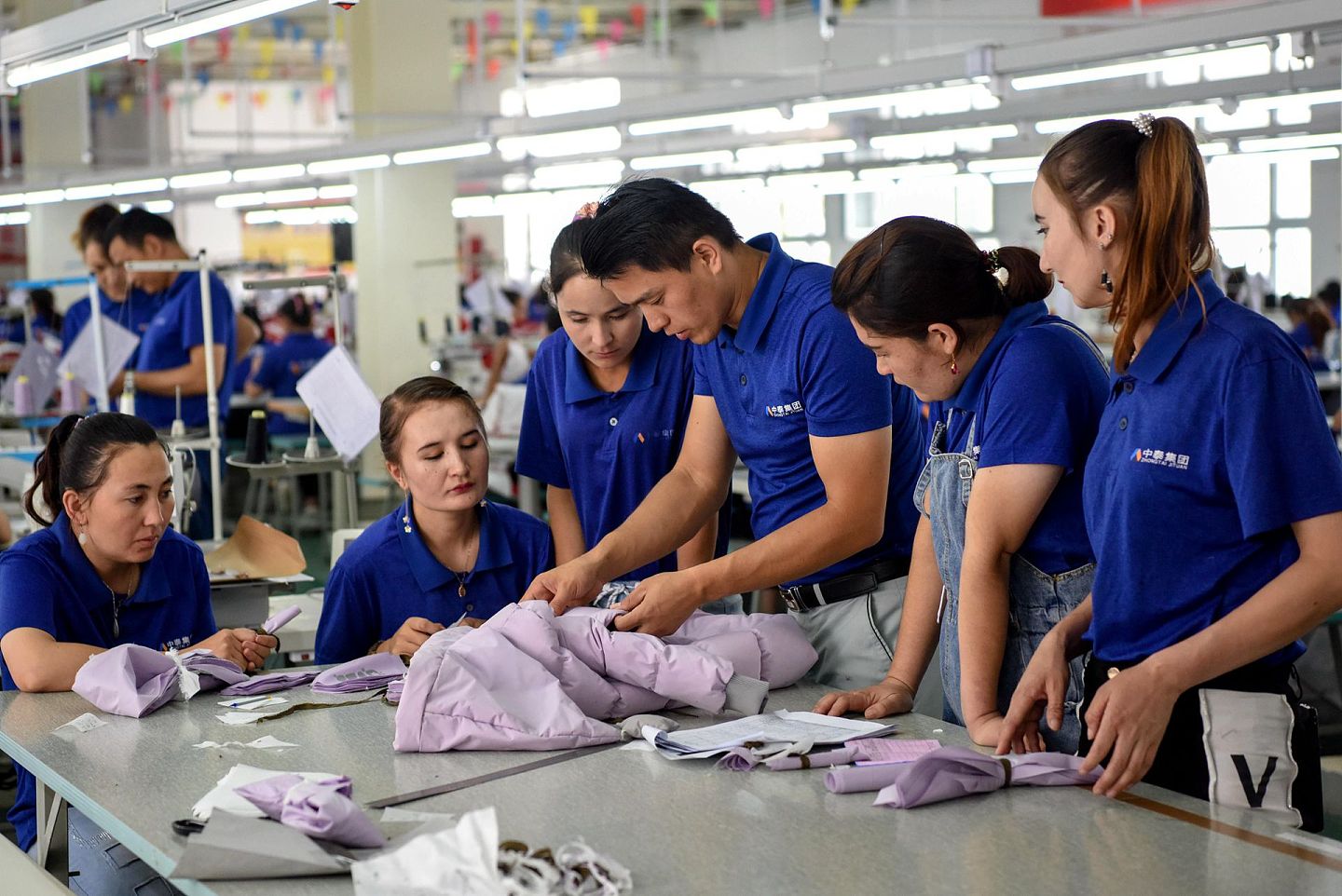 2019年8月25日，在新疆和田一家服装公司，技术员麦提托合提·艾克木（右三）在查看产品质量。（新华社）