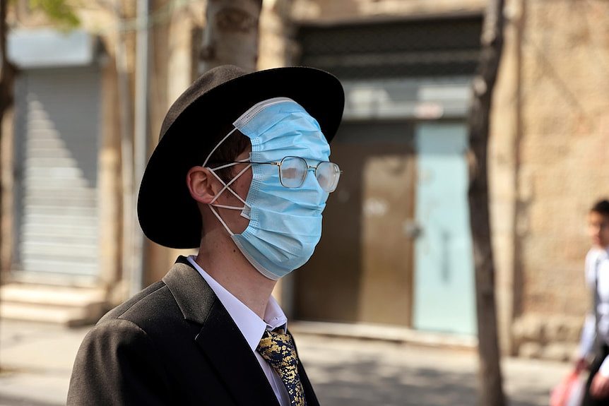 A man uses three masks to cover his whole face, with holes cut out so he can see