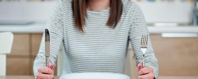 A woman sits at a table with an empty plate