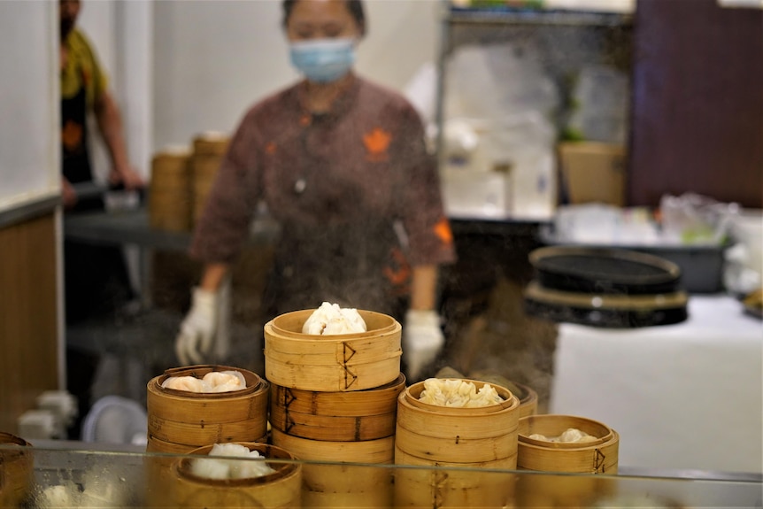 .A Landmark restaurant staff member in the background of a restaurant kitchen with bamboo bowls and dumplings