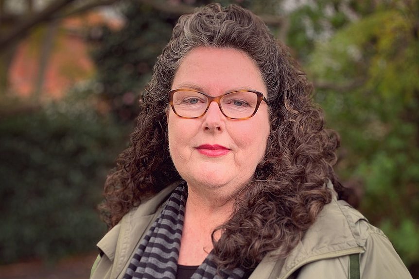 A woman in spectacles in a park.