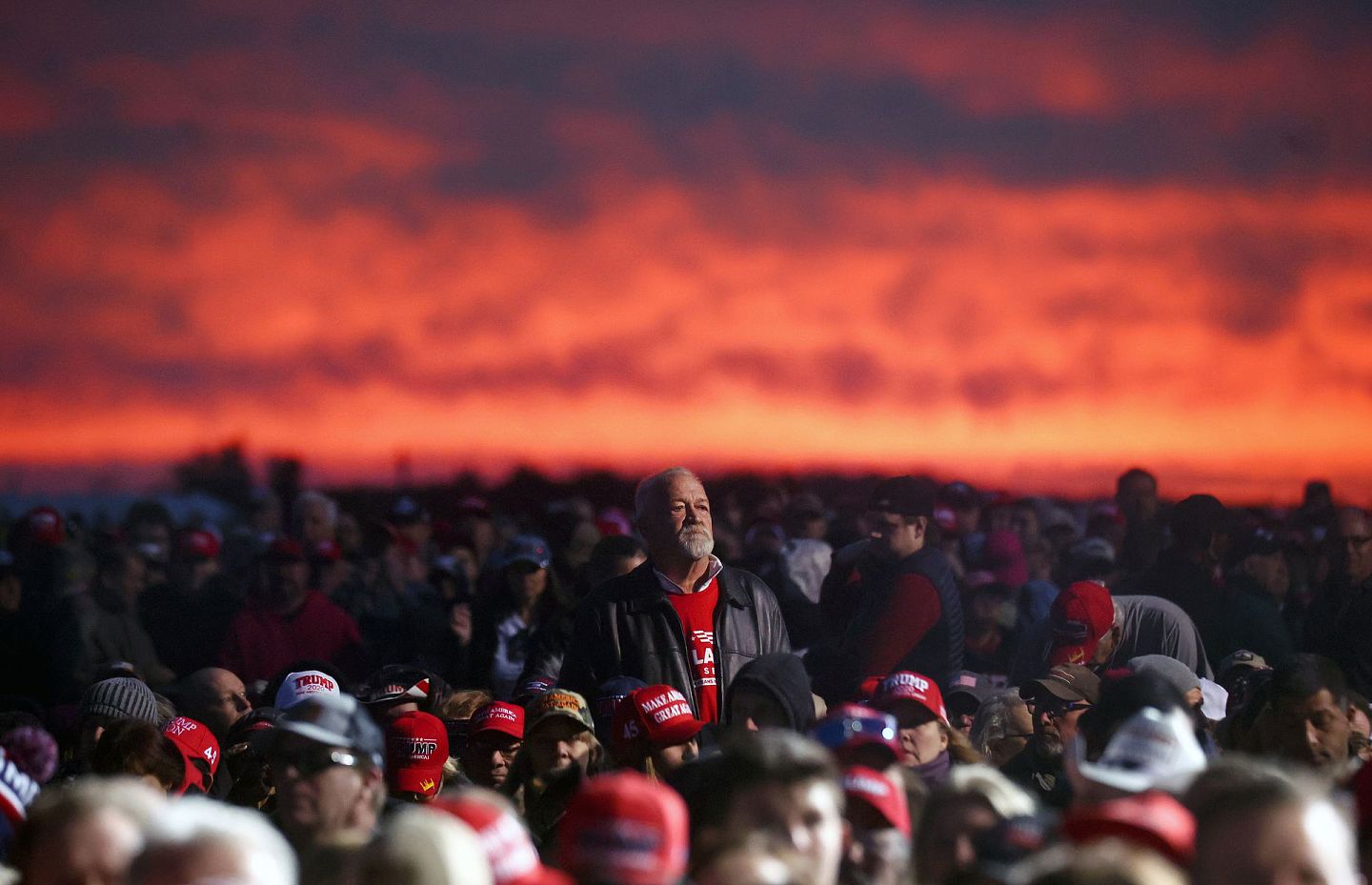 夕阳在牧场外的天空映出一片红，底下黑压压的都是来支持特朗普的人。（Getty Images）