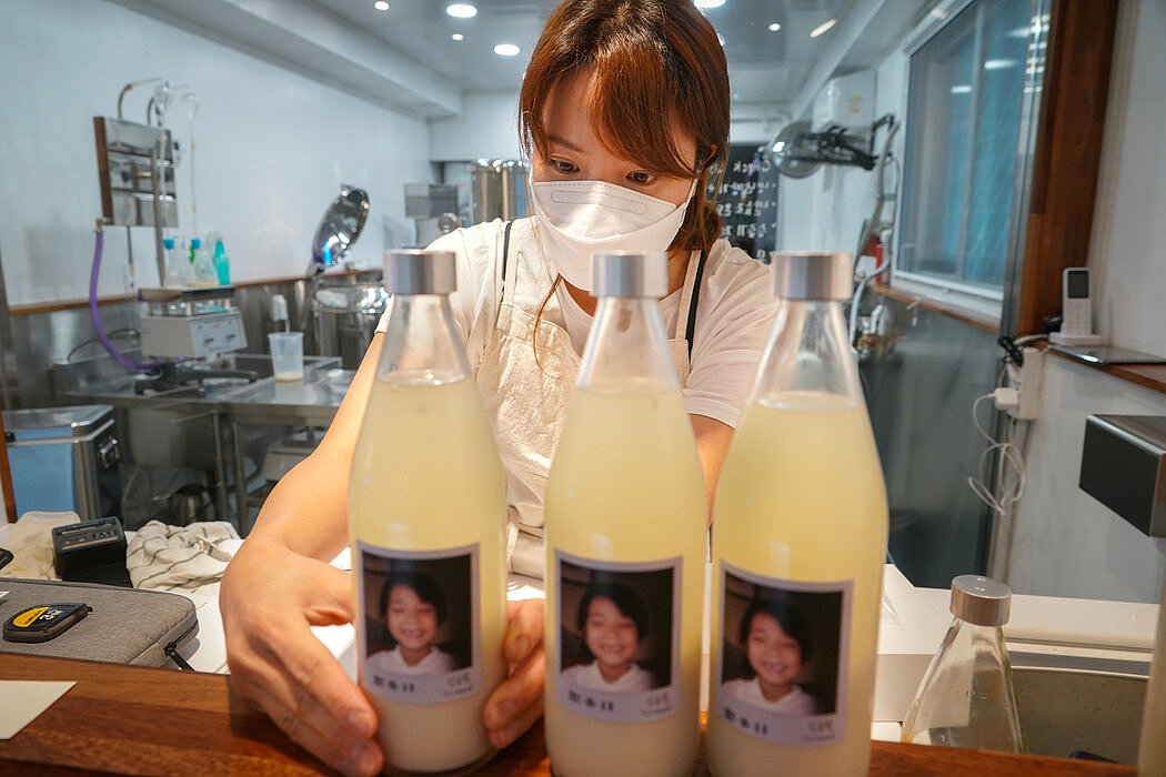 今年6月，Hanayangjo的老板韩阿英给在首尔制作的马格利酒瓶上贴标签。