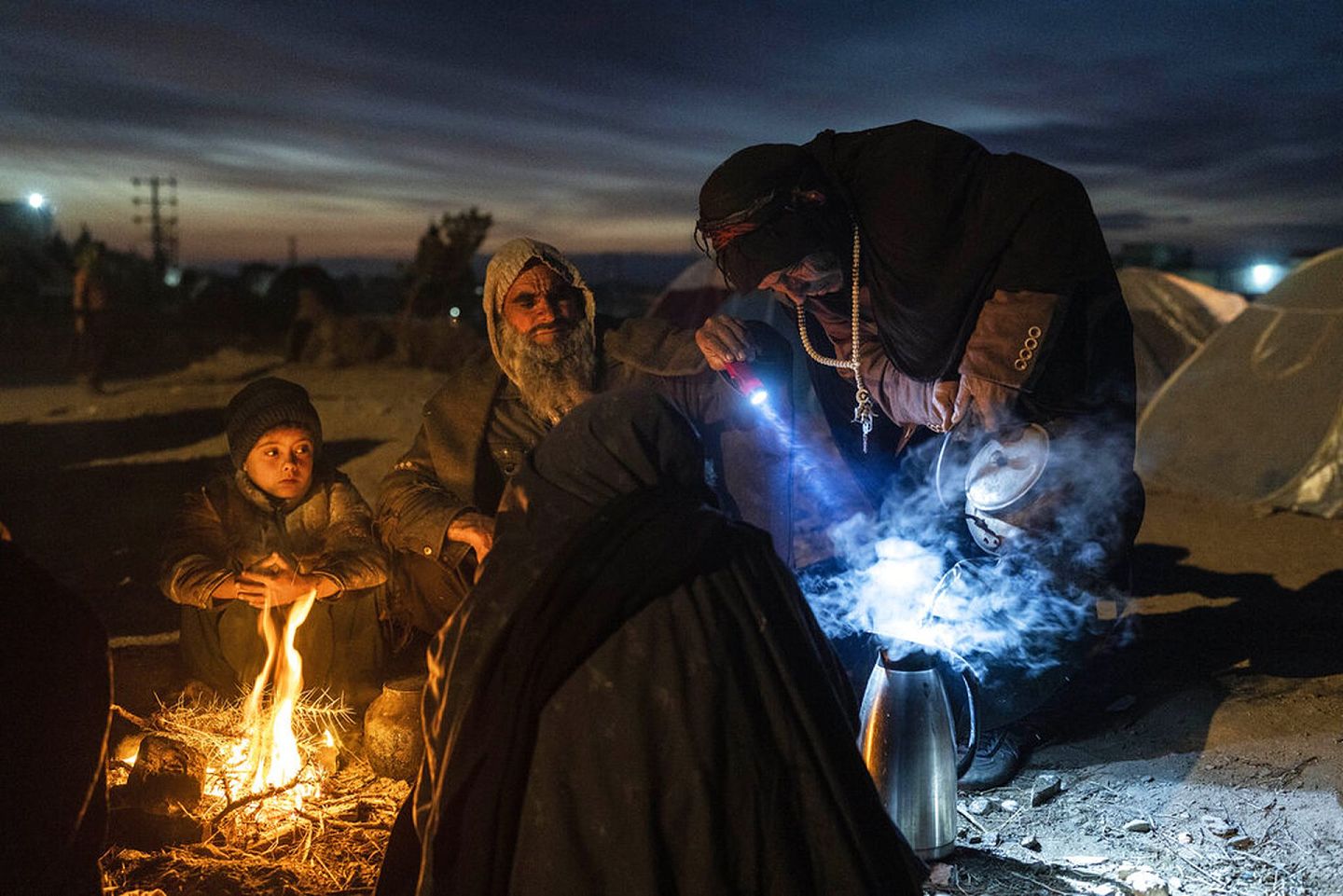 2021年11月29日，在阿富汗赫拉特，一个家庭在他们扎营的灾害局办公室外准备茶水。随着冬季的深入，阿富汗的严峻形势正在恶化。随着美国支持阿富汗政府的倒台和塔利班的接管，冰冷的气温加剧了螺旋式下降的痛苦。援助团体和国际机构估计约有2300万人（占全国的一半）面临严重的饥饿，近900万人处于饥饿的边缘。（AP）