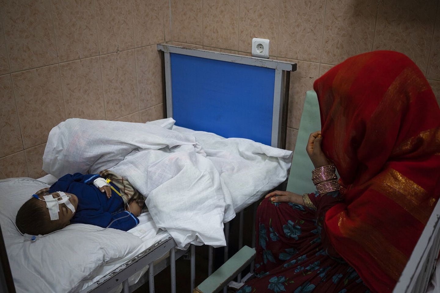 2021年11月8日，在阿富汗喀布尔的Indira Gandhi 医院，Walima看着她营养不良的1岁儿子哈利勒。联合国世界粮食计划署高级官员Mary-Ellen McGroarty 说，阿富汗正面临着一场“饥饿海啸”。2022年1月13日，粮食计划署敦促国际社会将政治讨论与人道主义需要分开，确保阿富汗所需的数十亿援助。(AP)