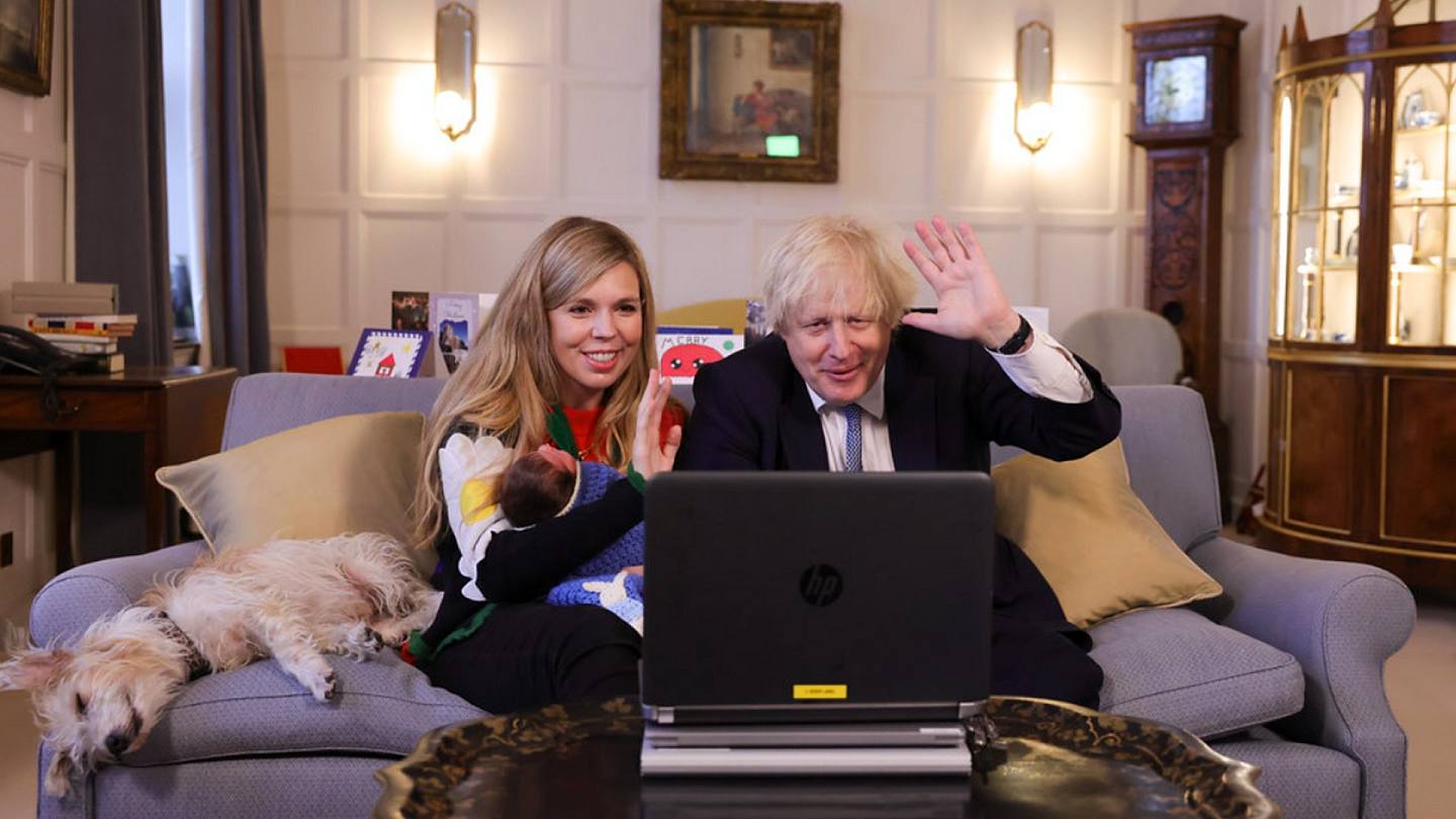 圖為英國首相約翰遜（右）的妻子西蒙茲（左）抱着女兒羅米。夫婦倆面對手提電腦屏幕，進行視像通訊。（英國首相府）