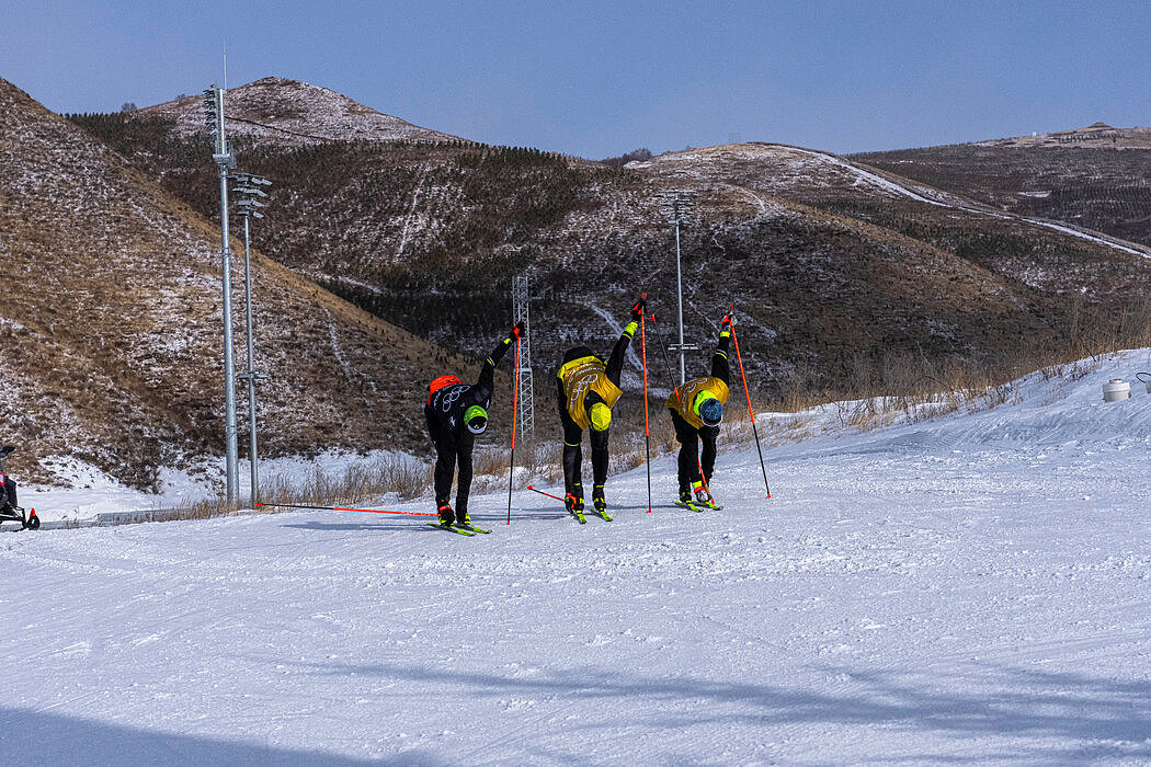 运动员在张家口的国家越野滑雪中心进行训练。一天前，小雪将附近的山头覆盖。