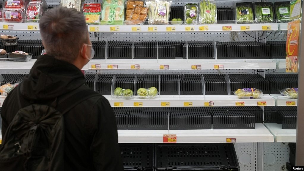 香港沙田区一家超市里，一位戴口罩的顾客望着半空的货架。香港新冠病毒感染猛增，创下最高纪录。（2022年2月7日）