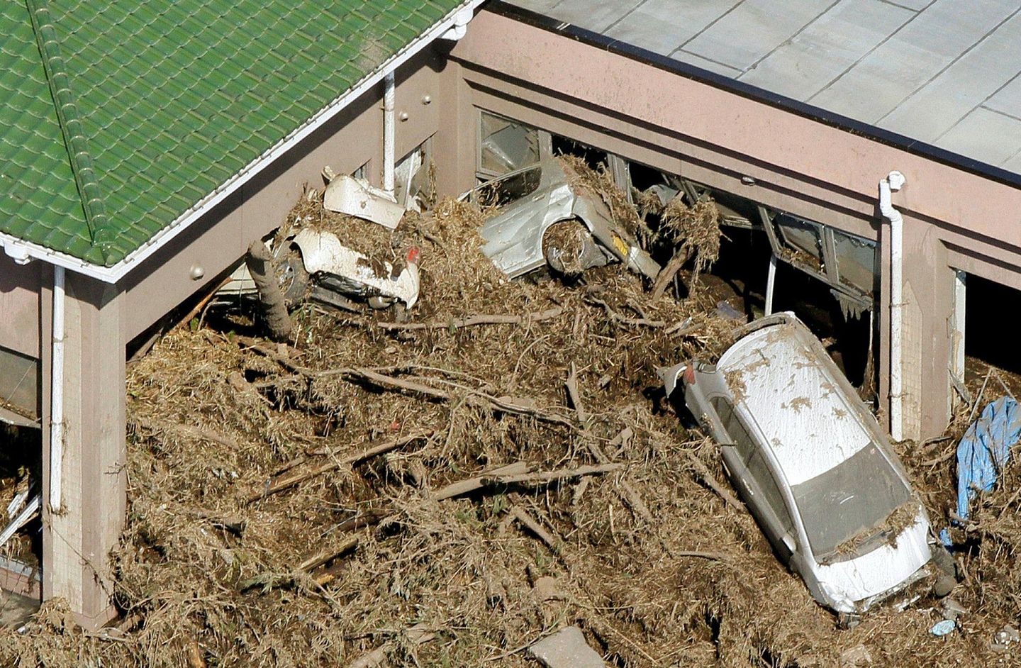 2011年3月12日，日本福岛县，南相马巿遭受海啸冲击，汽车、树木被水冲走，堆积在建筑物旁边。（路透社）