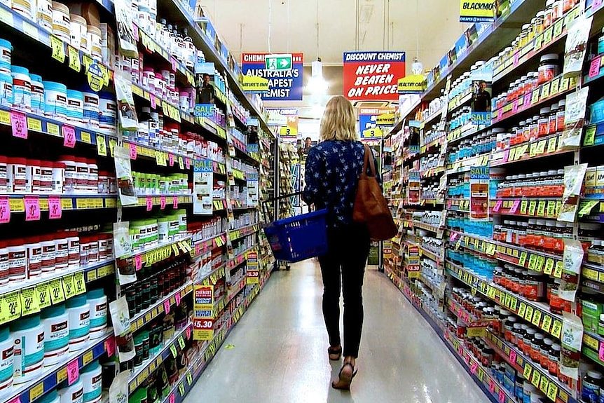 A woman walks down the aisle of a chemist