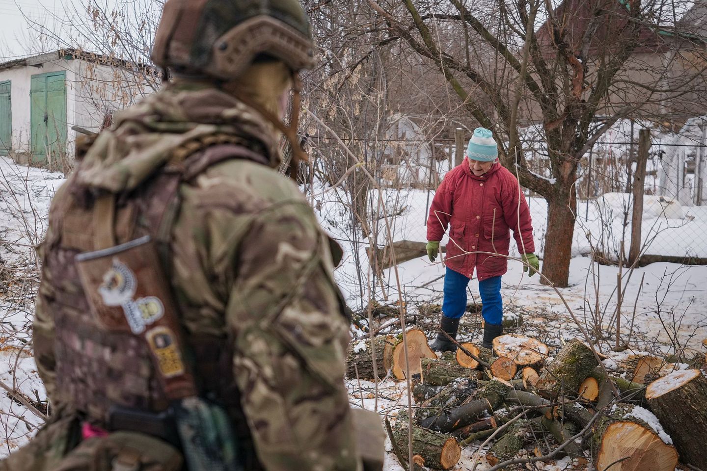 2022年2月7日，一名乌克兰军人注视着安娜·皮利皮夫娜（Anna Pylypivna），她是少数没有离开乌克兰东部前线村庄 Novooleksandrivka 的居民之一，正在处理柴火。（美联社)