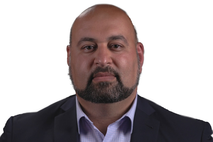 HEadshot of a man wearing a black suit jacket and button-up shirt against white background