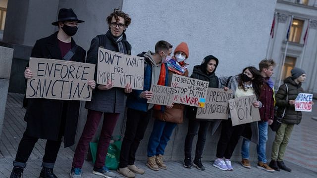 A group of people hold signs at the front of the Ukrainian Foreign Ministry during a protest calling for the European Union to impose additional sanctions