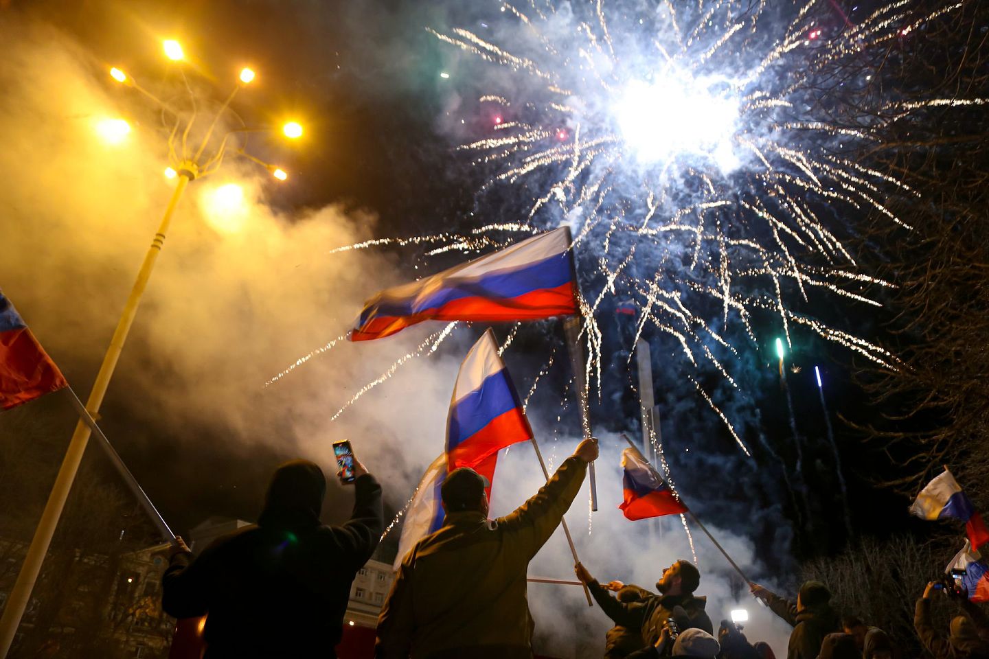 2022年2月21日晚些时候，在乌克兰东部亲俄武装控制的顿涅茨克市中心，人们挥舞着俄罗斯国旗庆祝被承认独立。(美联社)