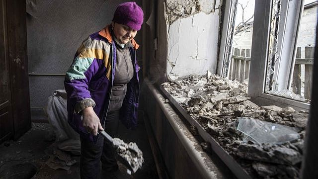 在俄罗斯支持的叛军控制的顿涅茨克地区，一名妇女在炮火过后清理被破坏的房屋
