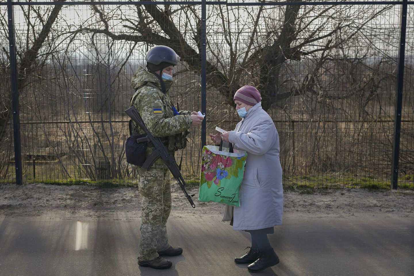 一位顿巴斯地区的归女从分离分子控制区进入乌克兰控制区，乌克兰士兵正查阅其证件。（美联社）