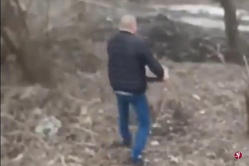 一名光头的乌克兰大叔徒手拿起一个地雷往路旁树林走去。（取自推特截图） 