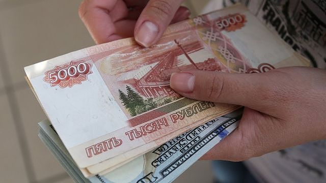 An employee holds 5000 ruble banknotes inside a foreign currency exchange bureau in Russia.