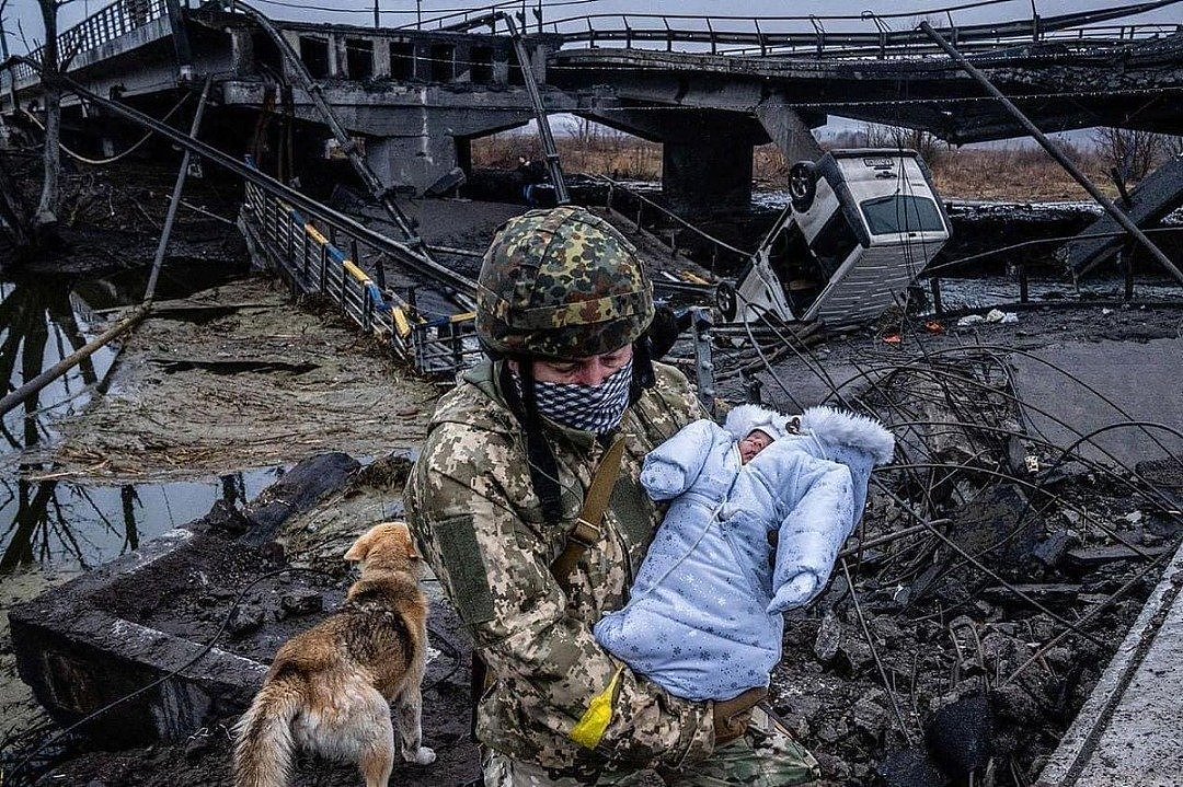 一名乌克兰士兵抱住一名婴儿过桥，撤离已经沦为废墟的伊尔平镇。（图取自Timothy Fadek推特）