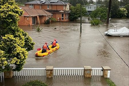 一艘橡皮艇漂在水面上，周围可以看到被淹了一半的房屋