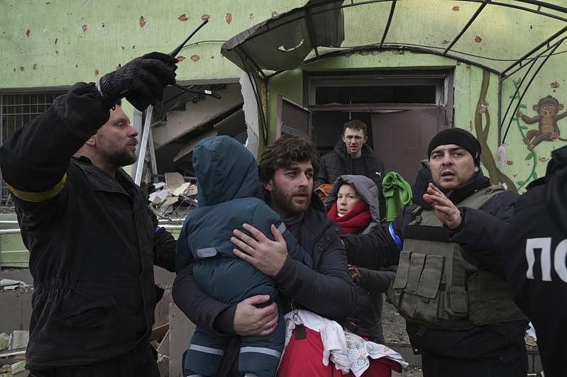 图为马立波市的急救人员和义工9日协助一名男子和他的孩子从一家遭俄军轰炸的妇产科医...