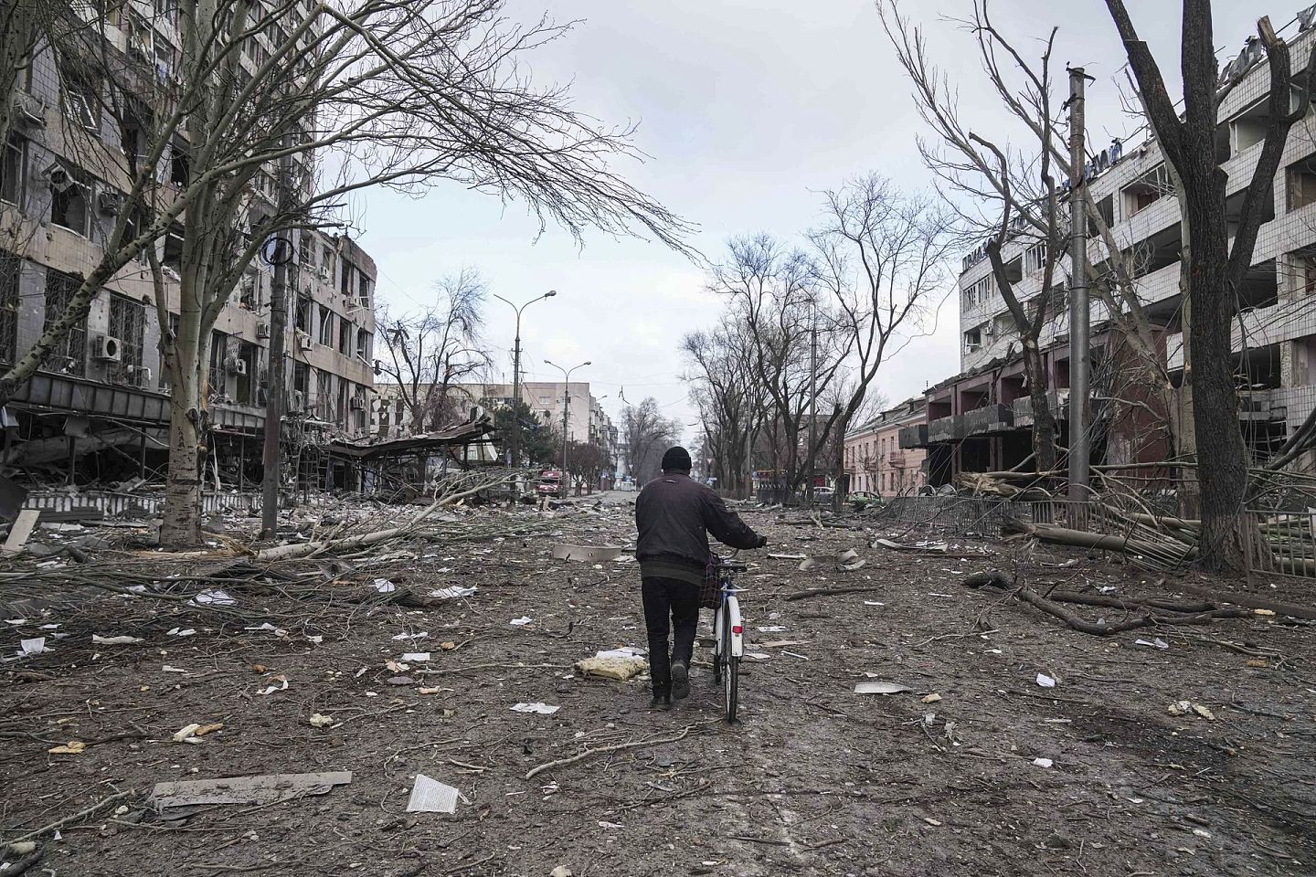 2022年3月10日，一名男子骑着自行车在乌克兰马里乌波尔（Mariupol）被炮击损坏的街道上行走。（AP）