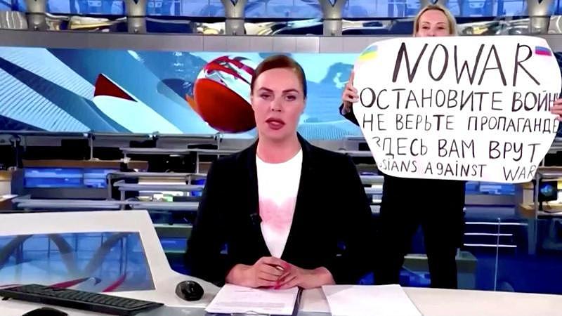 俄罗斯国营电视台14日直播时，一名女子闯入高举反战标语。(路透)