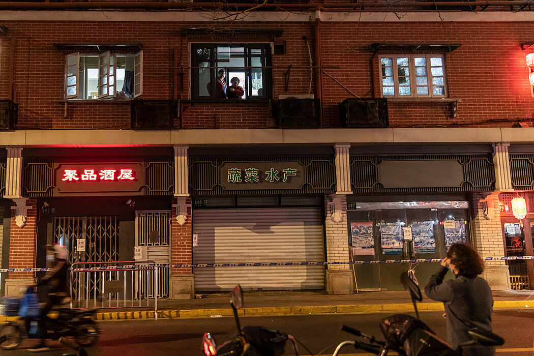 在上海一栋被封锁的大楼里，一名女子在街上与一对夫妇交谈。