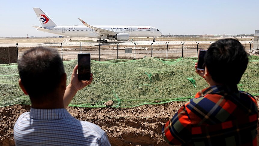 People watch a plane preparing to take off at an airport.