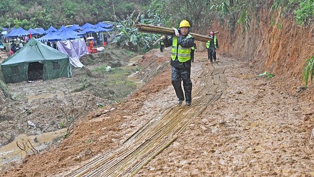 广西梧州藤县中国东航MU5735航班坠落事故坠落现场工作人员在铺上竹子的泥泞路面上行进（新华社图片23/3/2022）