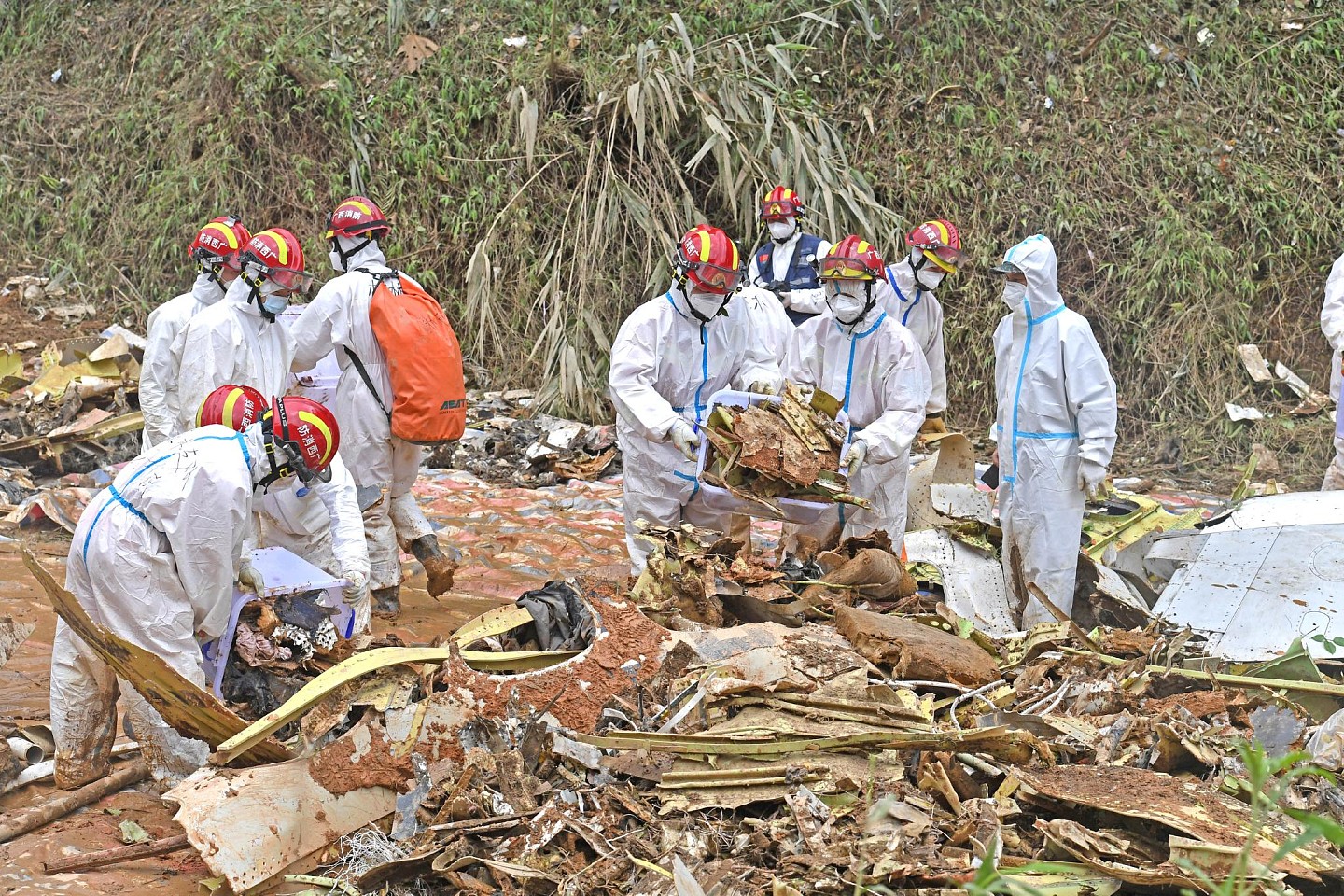 3月25日，搜救人员在事故核心现场搬运飞机残骸。来源：新华社