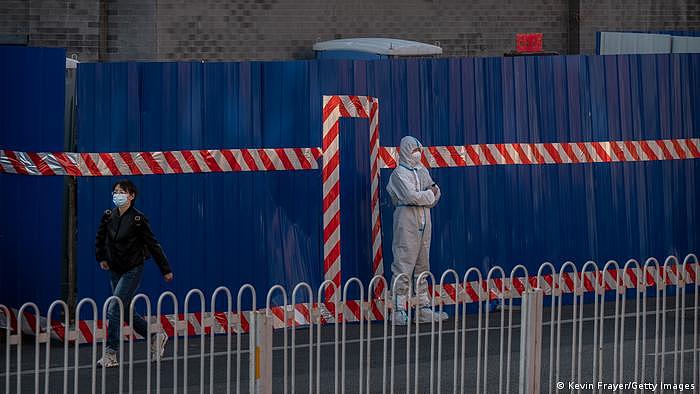 Ein Wachmann in Schutzkleidung vor dem Eingang eines abgeriegelten Stadtbezirks in Peking