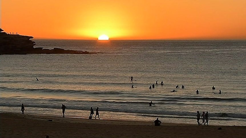 The sun rising above the horizon at Bondi Beach.