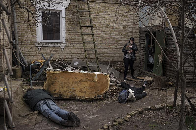 一名抱着猫的布查妇女在院子中发现数名罹难者。 (Getty Images)