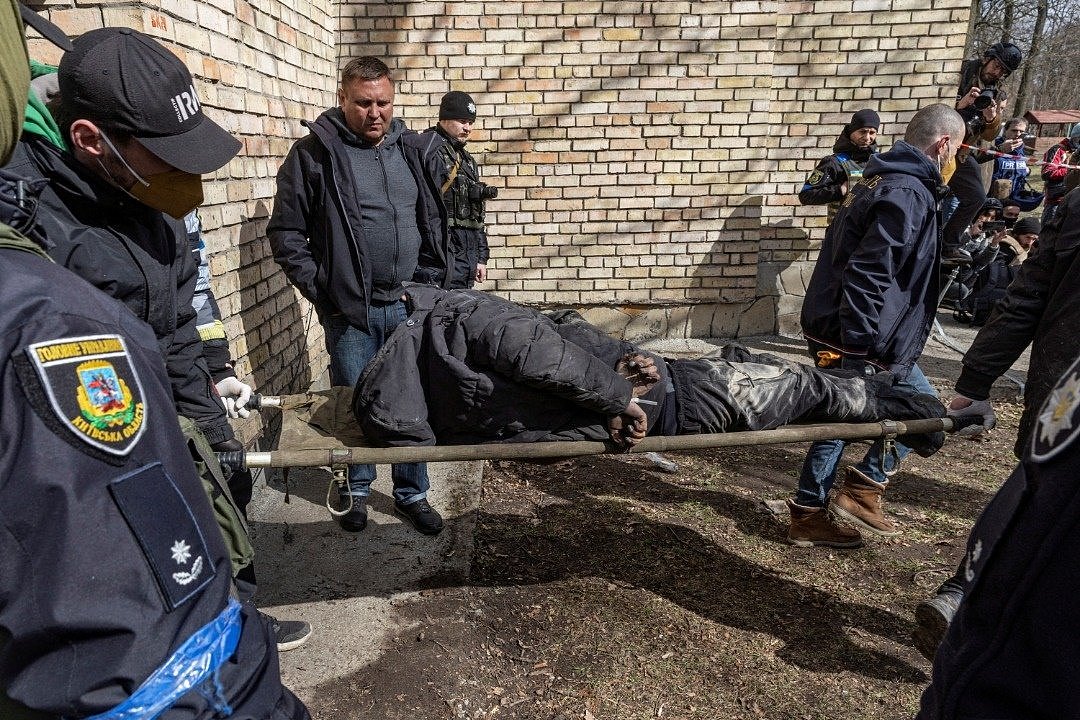 在乌克兰基辅郊外的布查镇，乌克兰军人从地下室抬出被发现的尸体。（图取自路透社）