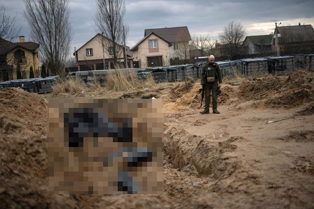 乌军在布查发现一处埋有大量尸体的坑洞，经过简单清理后为他们裹上尸袋。 一名乌军士兵正在为罹难者致哀。 （图／路透）