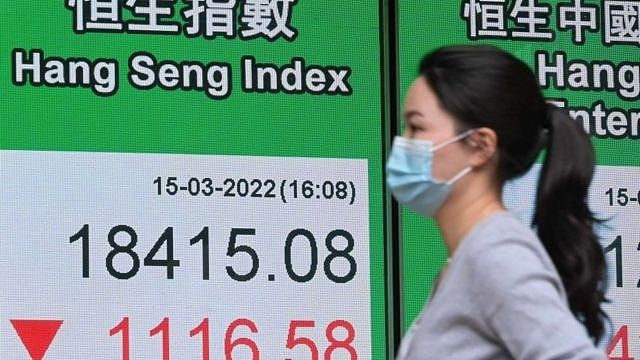 A pedestrian walks by an electronic screen displaying the Hang Seng Index on March 15, 2022 in Hong Kong, China.