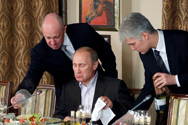 2011年11月的照片显示，普里戈津（左）在莫斯科附近的一个宴会上协助普京